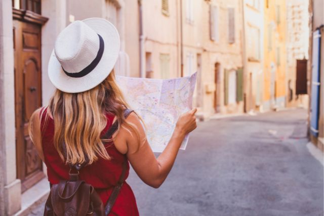 a woman stands in an empty street holding a map