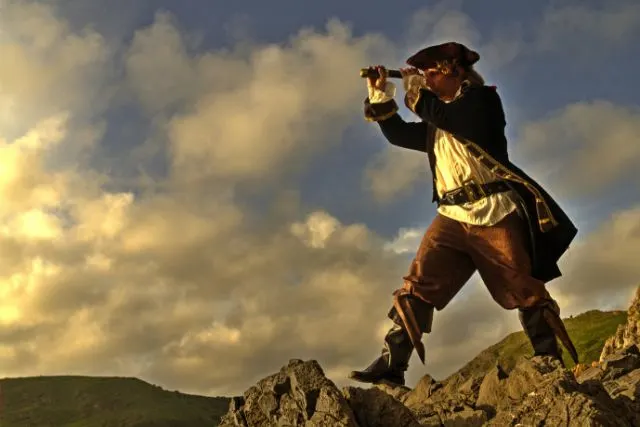 a man dressed like a pirate looks through a telescope