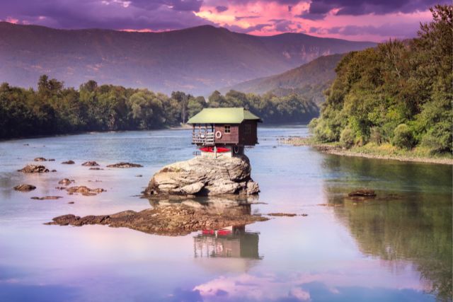 a house on a rock surrounded by water