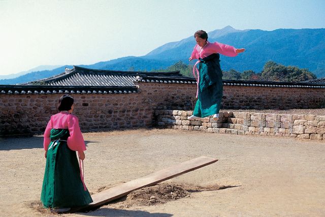 two women playing on a piece of wood