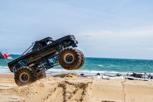 a monster truck does tricks on a beach