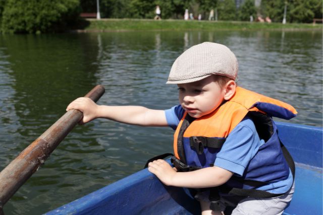 a little boy holds an oar in a boat
