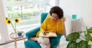 a woman sits in a chair with a notebook and writes